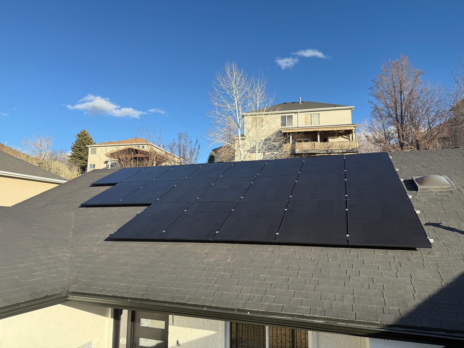 [black-on-black Trina panels] Scenic rooftop solar installation with mountain backdrop and clear weather conditions.