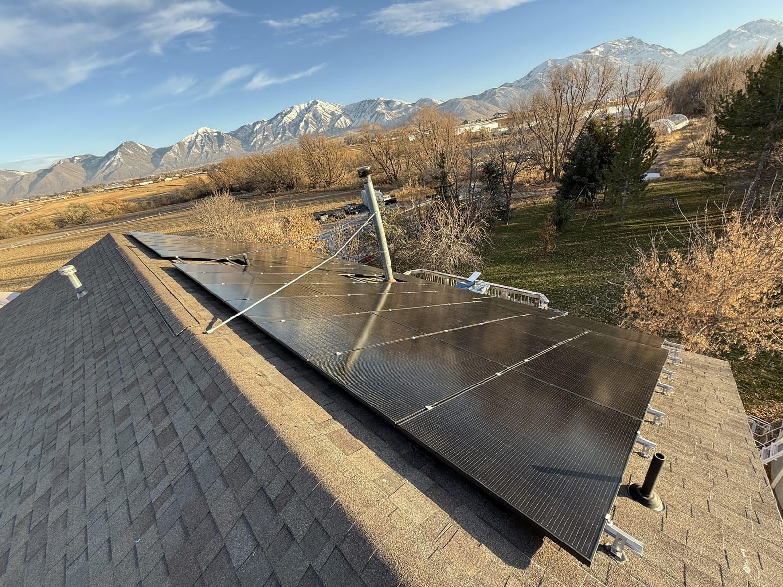 [Tier 1 Trina panels] Sideways shot of ground-mounted solar array with racking structure and residential property in background
