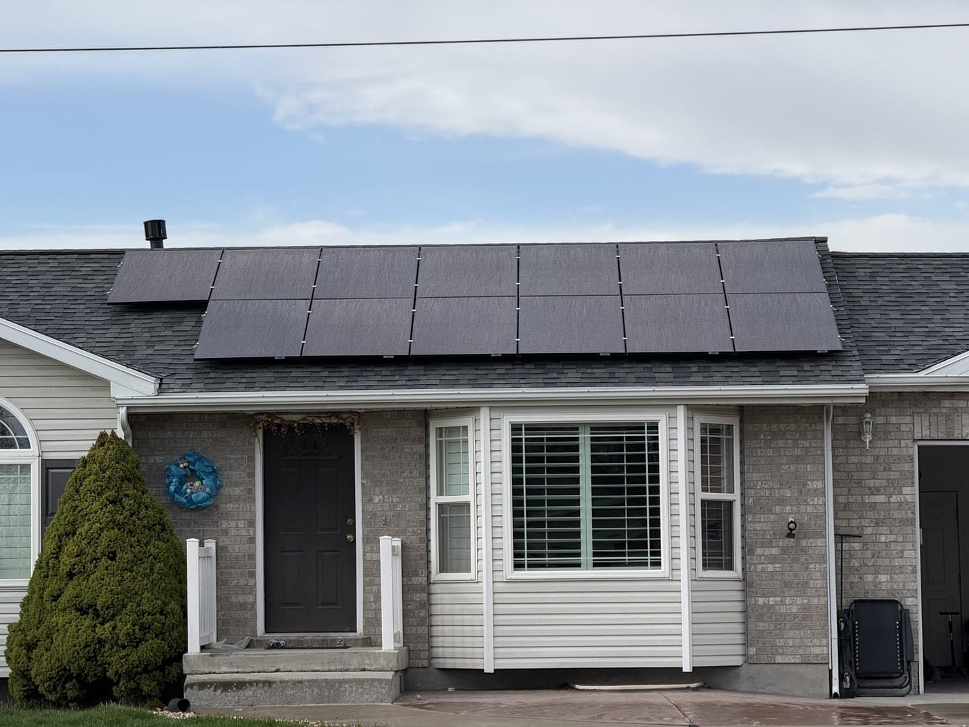 [black-on-black panels] House front with solar panels visible on roof, good framing