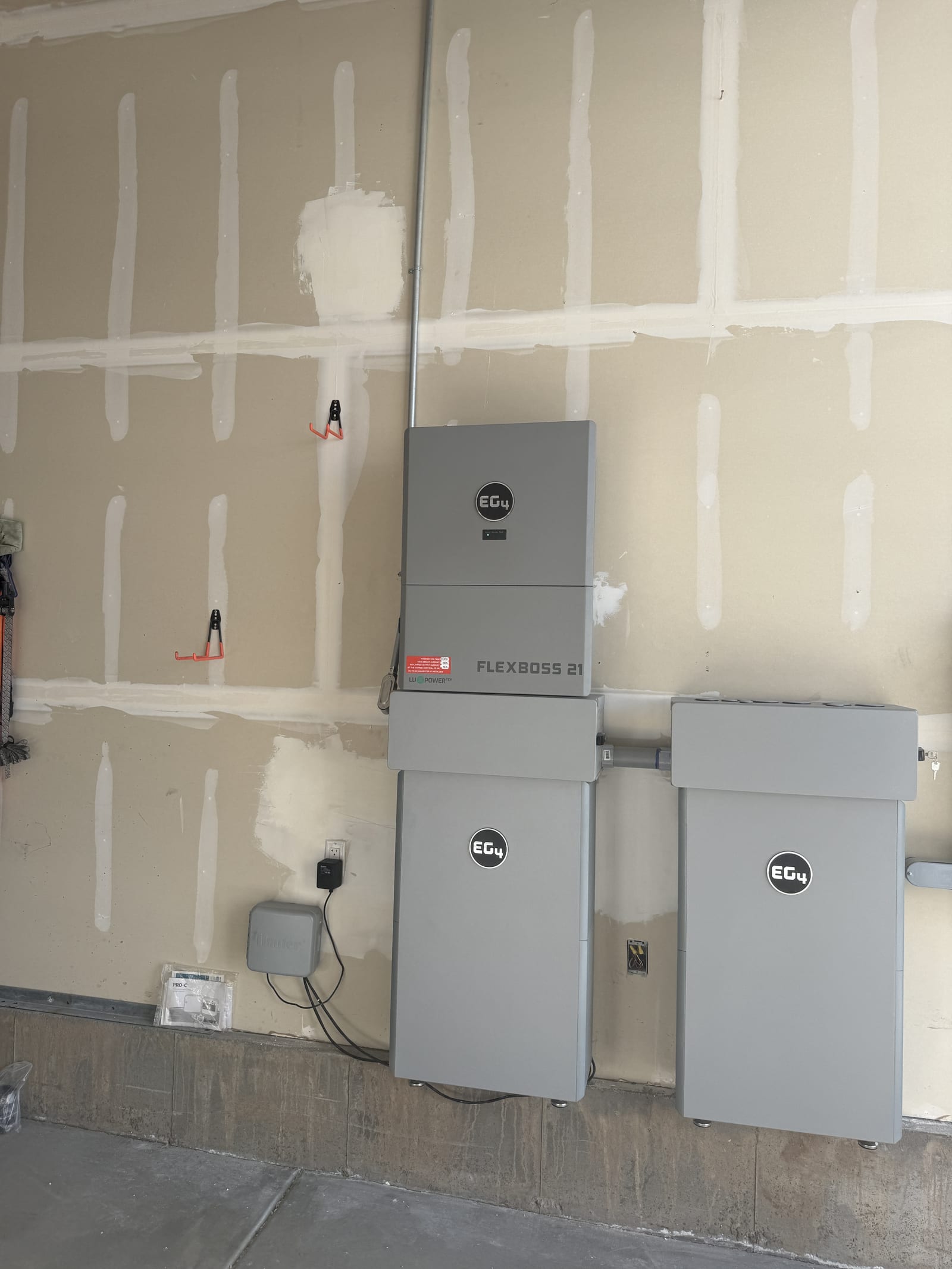 EG4 FlexBOSS 21 inverter and EG4 battery units on unfinished garage wall