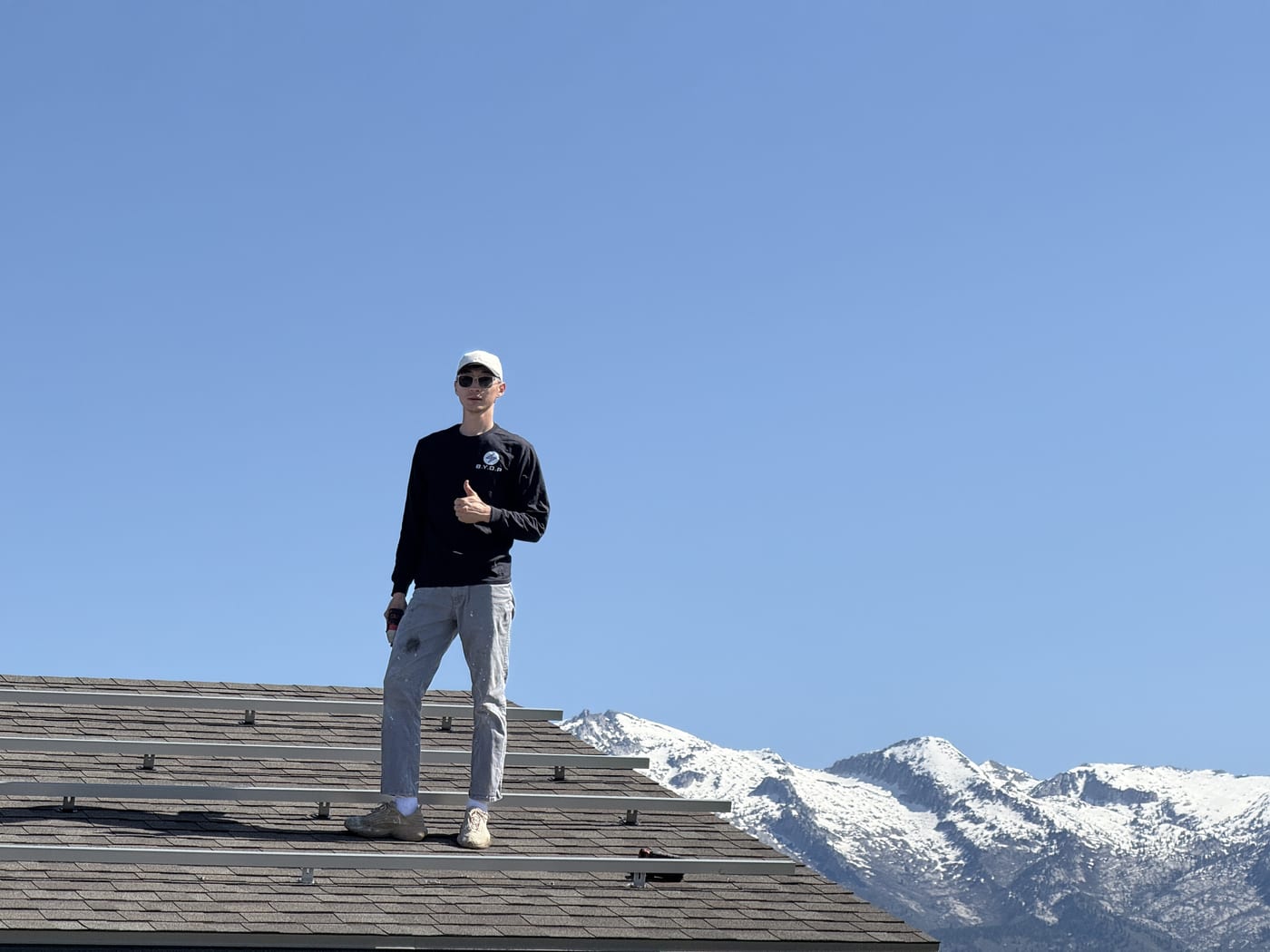 BYOP installer on roof with partially installed solar panels and mountain scenery