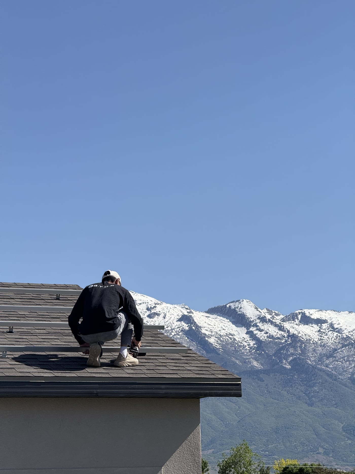 BYOP crew member on rooftop with solar panels and mountain landscape in background