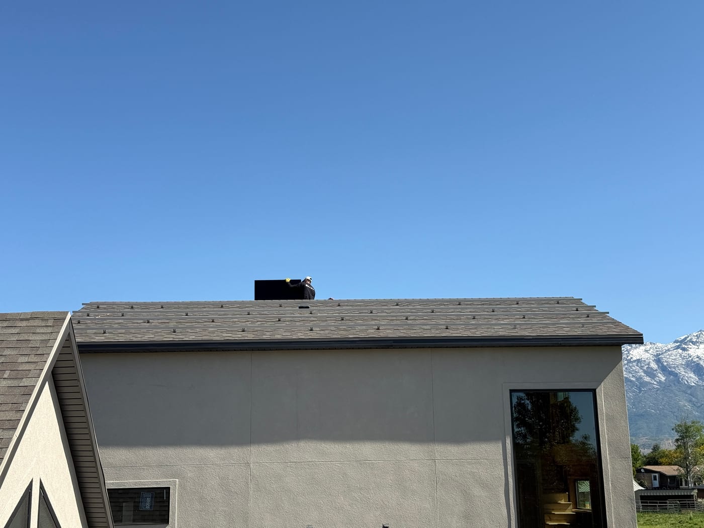 House exterior with worker on roof during racking installation and mountain backdrop