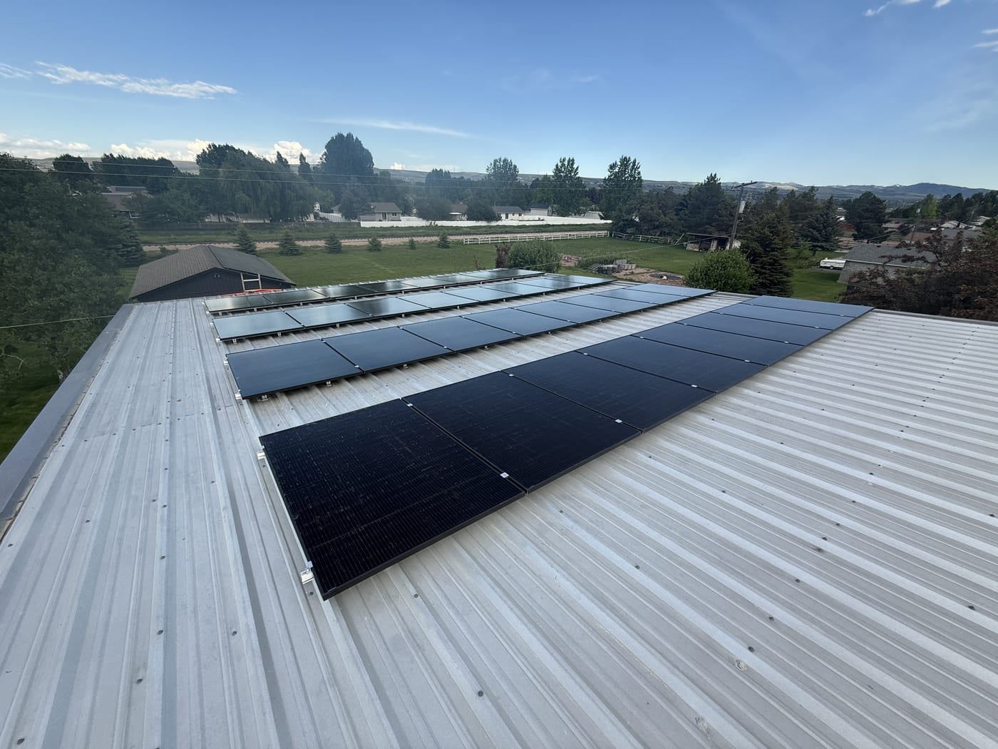 Solar panels on metal roof with wide rural Idaho landscape and blue sky in background