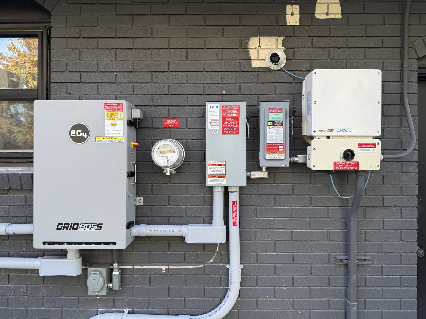 EG4 GridBOSS system with meter base and safety disconnects on painted brick wall