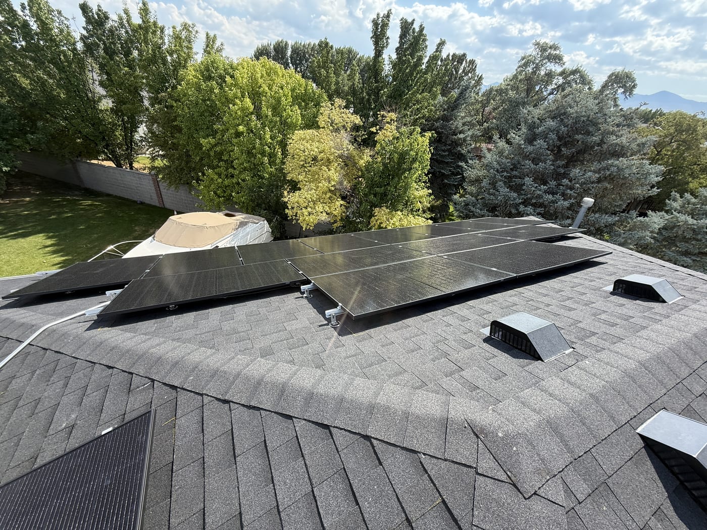 Solar panels partially installed on dark shingle roof showing two roof planes with vents