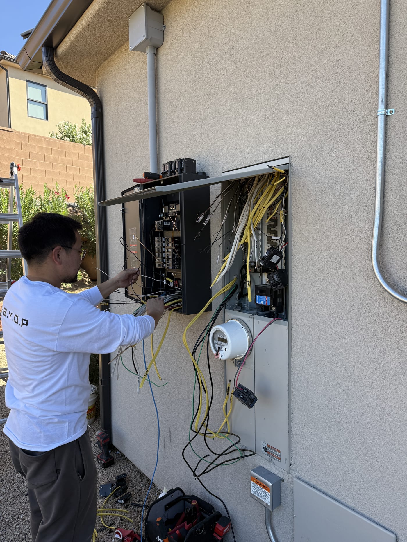 BYOP crew member wiring EcoFlow DPU inverter panel on exterior wall under eave