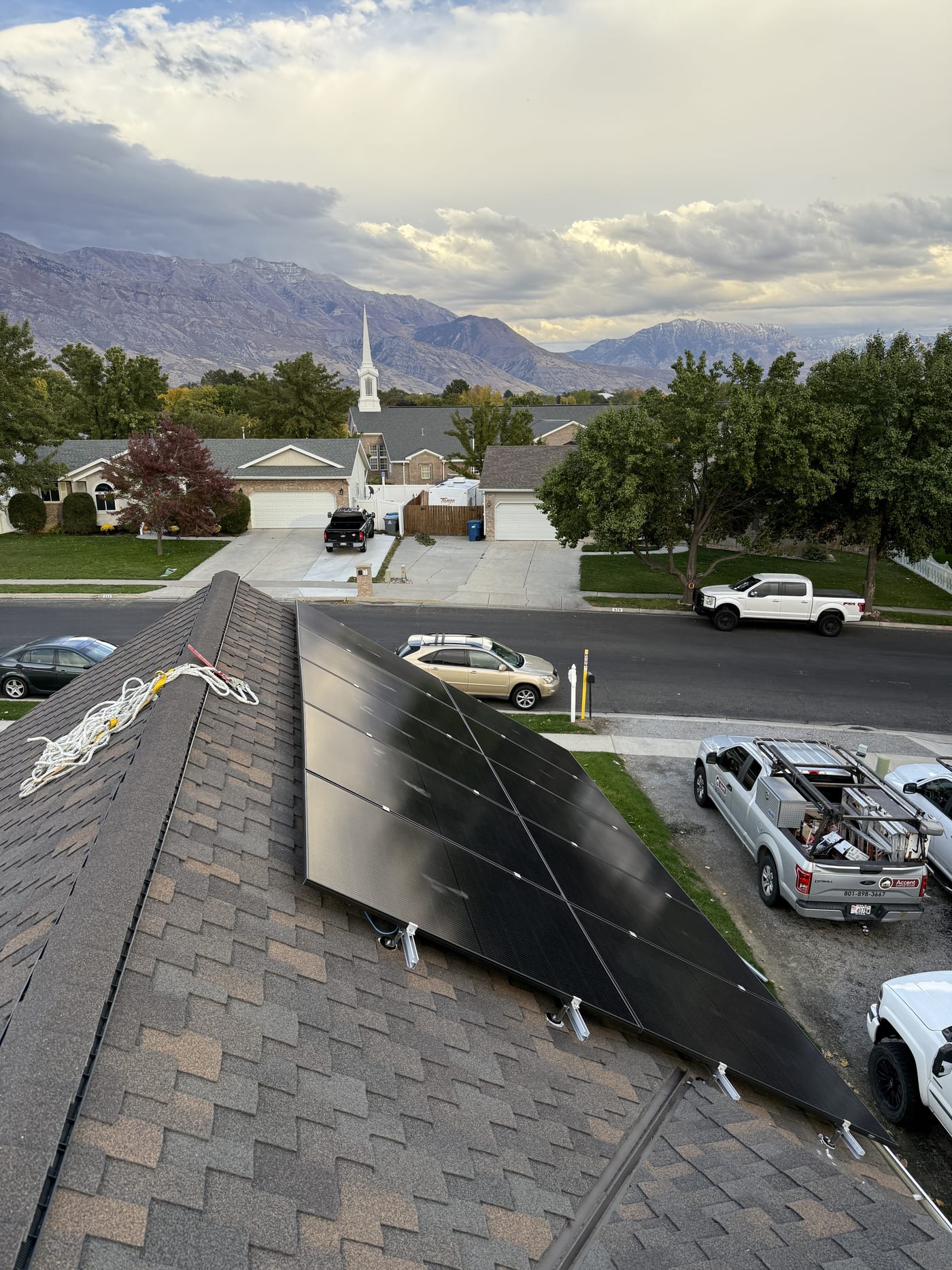 [Trina panels] Solar panels on front roof looking down to street with work trucks and mountain views