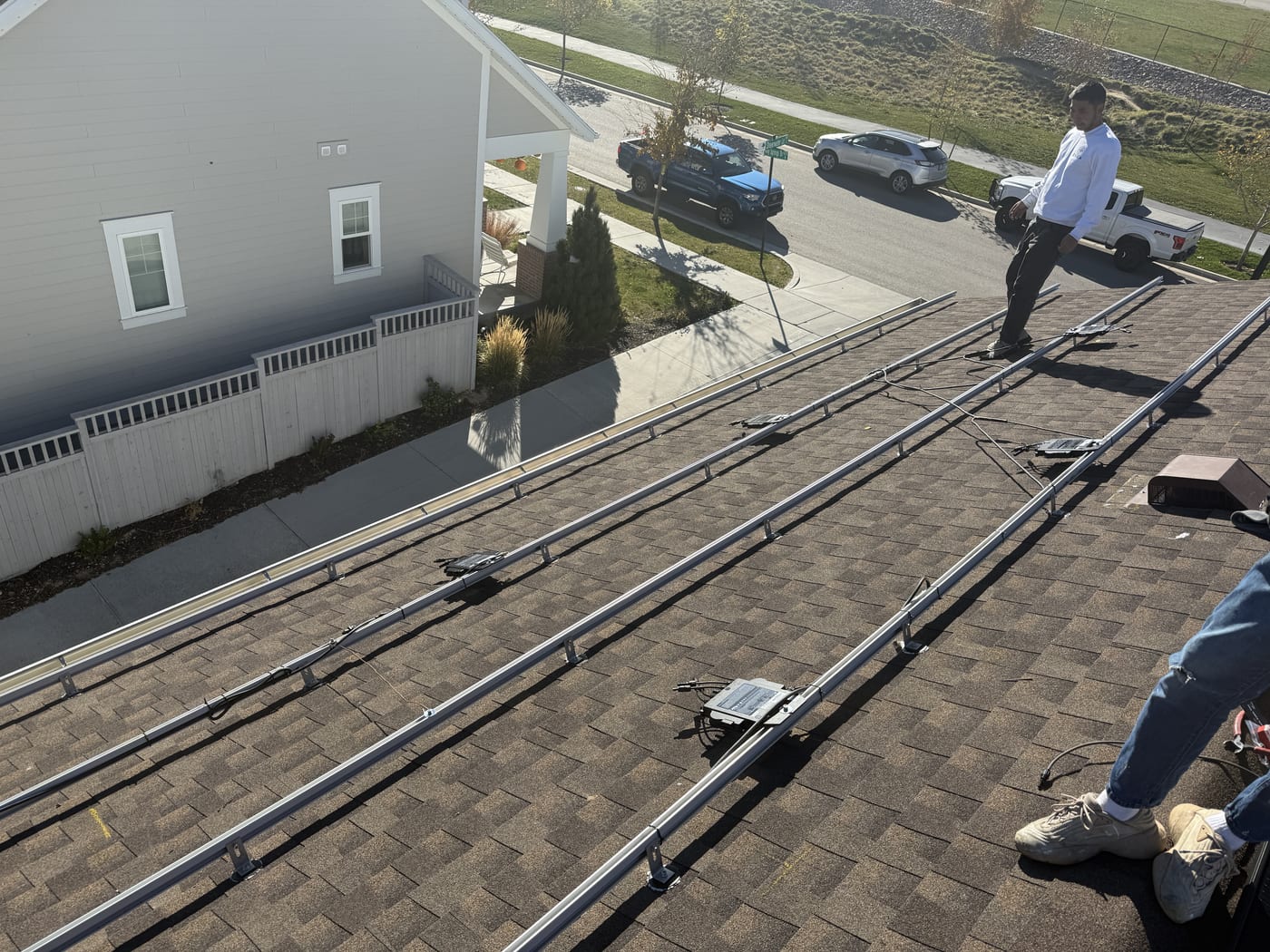 Wide roof view with racking and microinverters during installation with crew on ground below