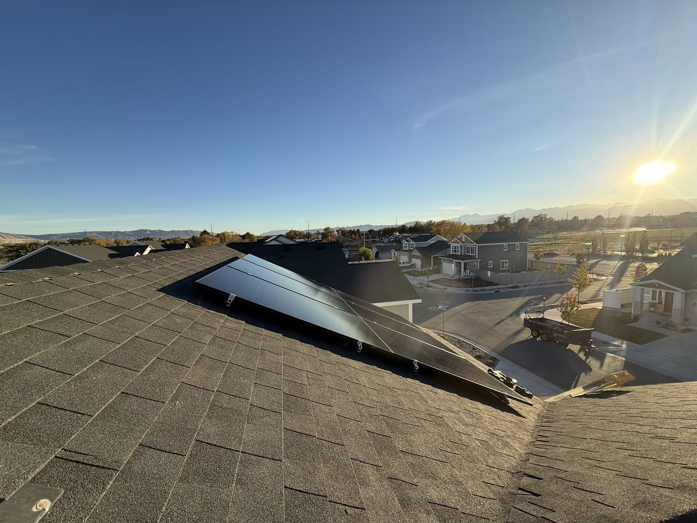 [Tier 1 Trina panels] Solar panels on roof with golden hour sunlight and neighborhood houses in background