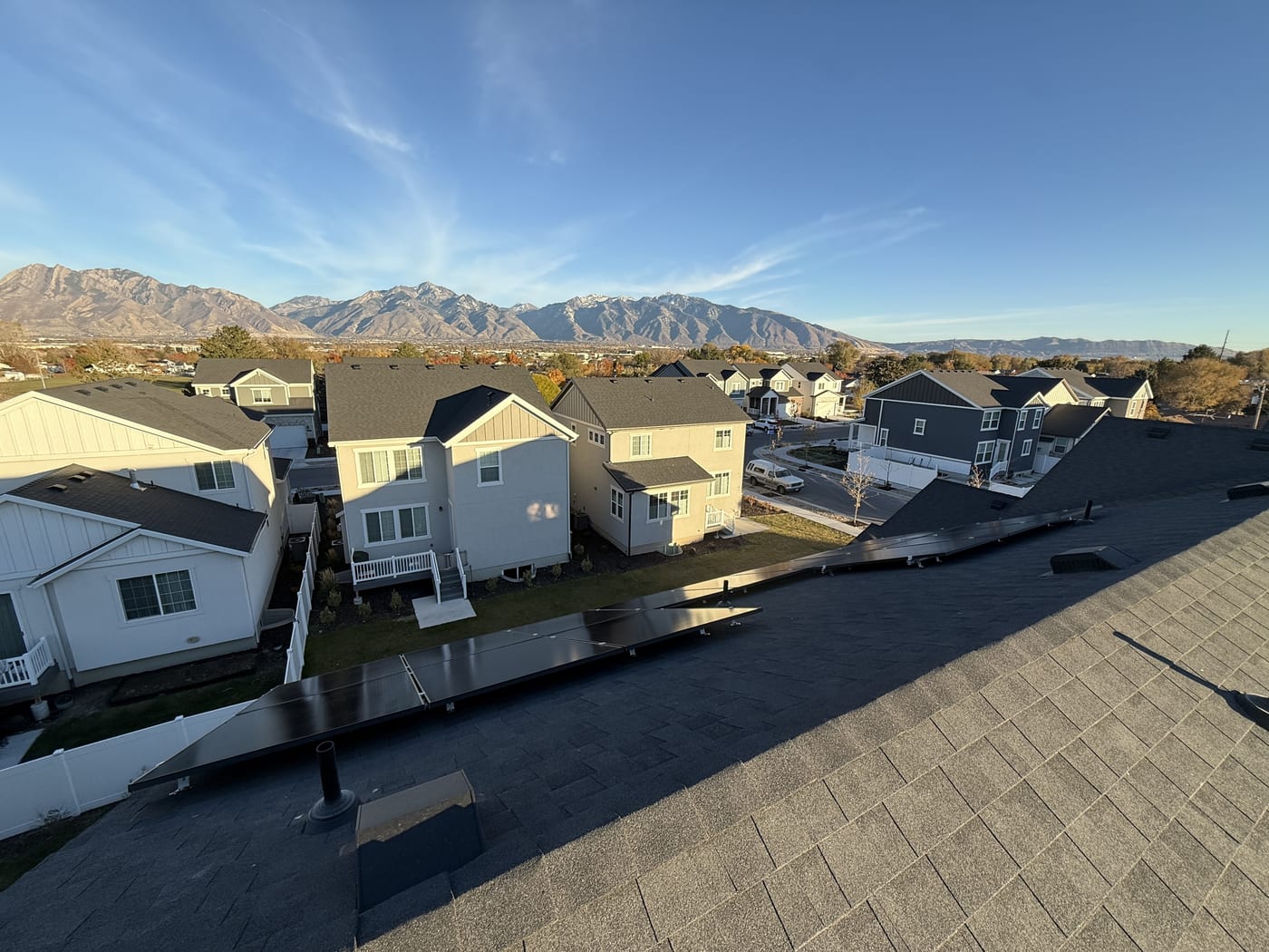 [Tier 1 Trina panels] Solar panels on roof edge with Wasatch mountains and neighborhood visible in background
