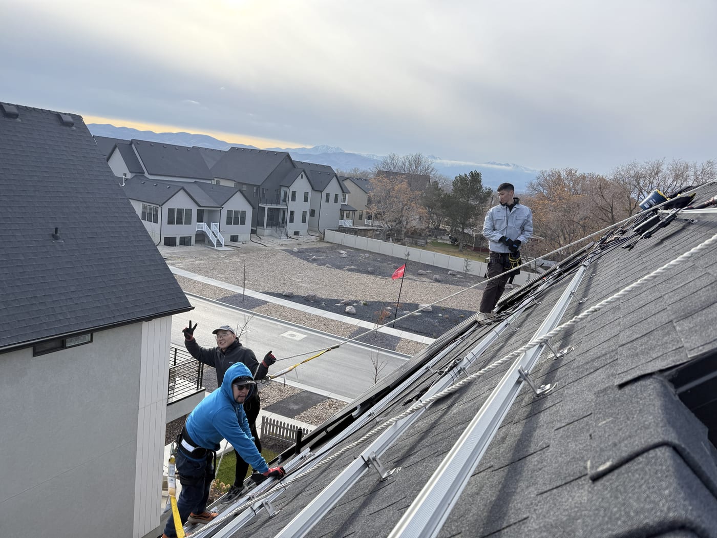 [Tier 1 Trina 410W black-on-black panels] Crew installing panels on racking at golden hour, neighborhood and sunset light visible below