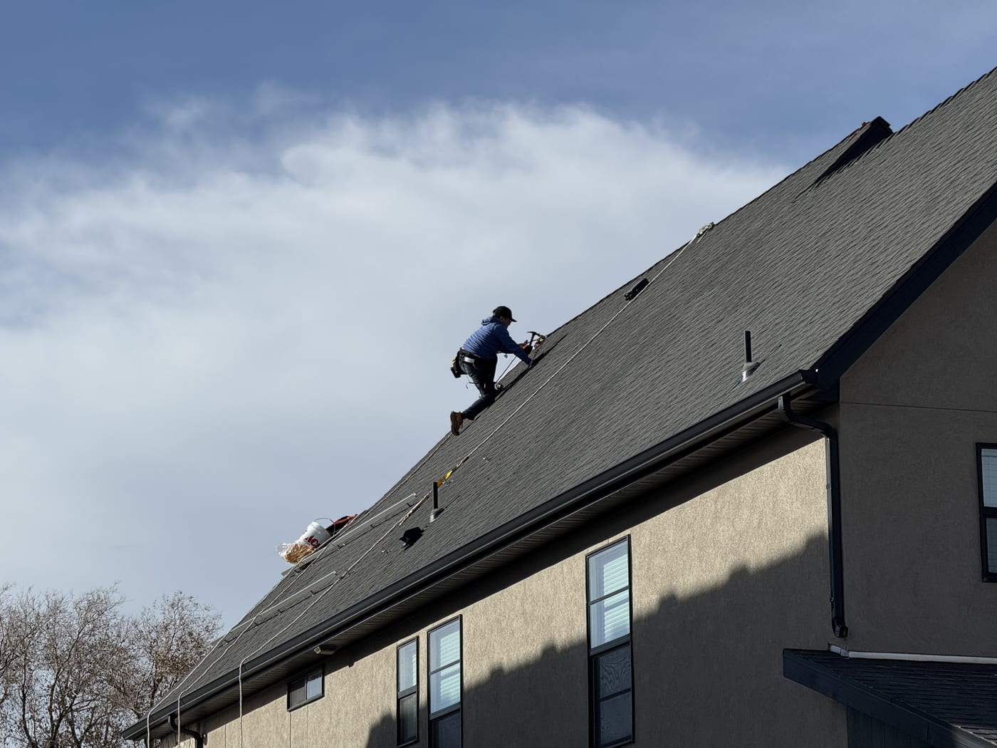 House exterior with two crew members visible on roof, similar angle to previous shot
