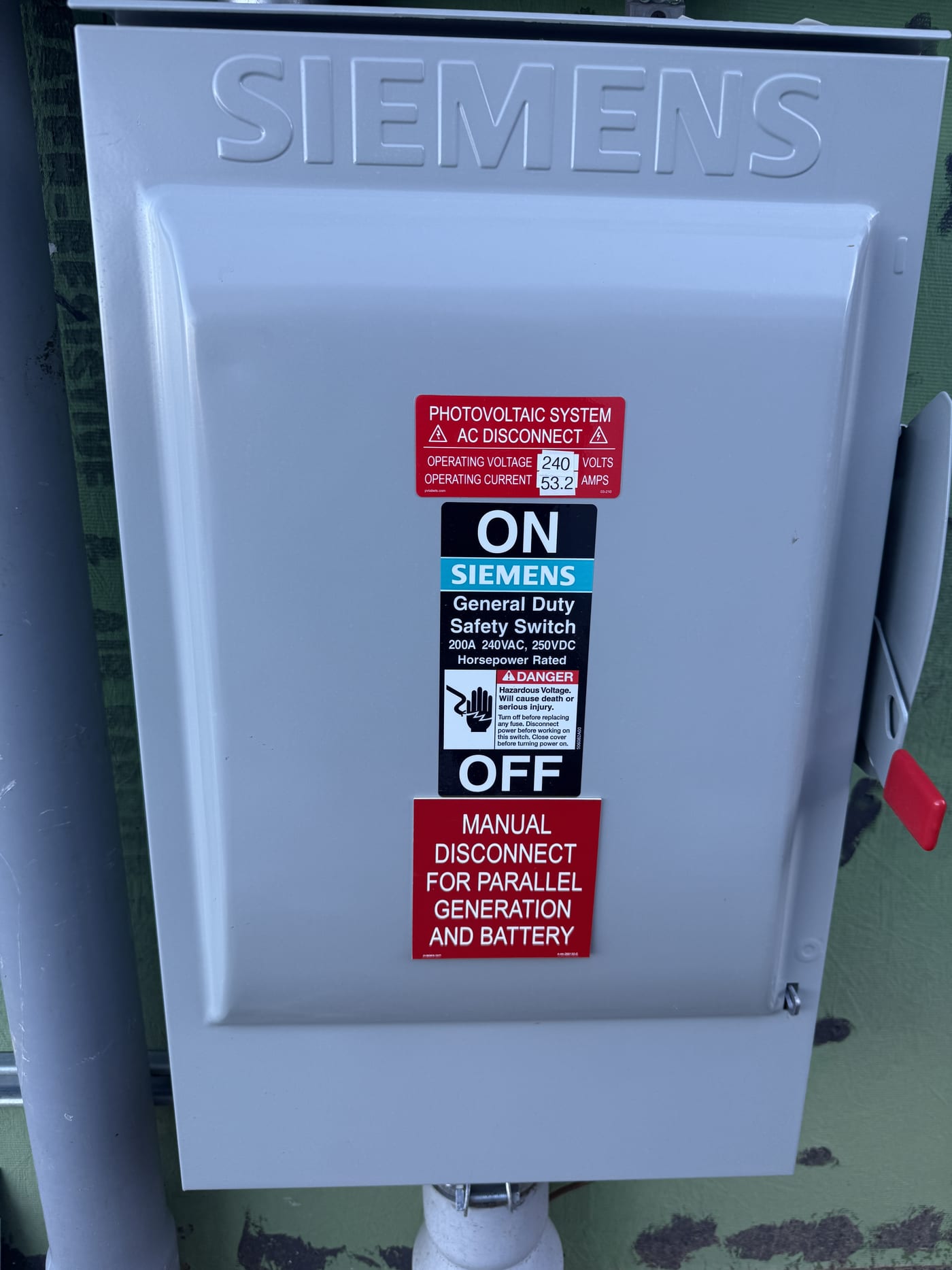 Close-up inside disconnect panel showing red safety disconnect, fuse, ground wire, and copper bus connections