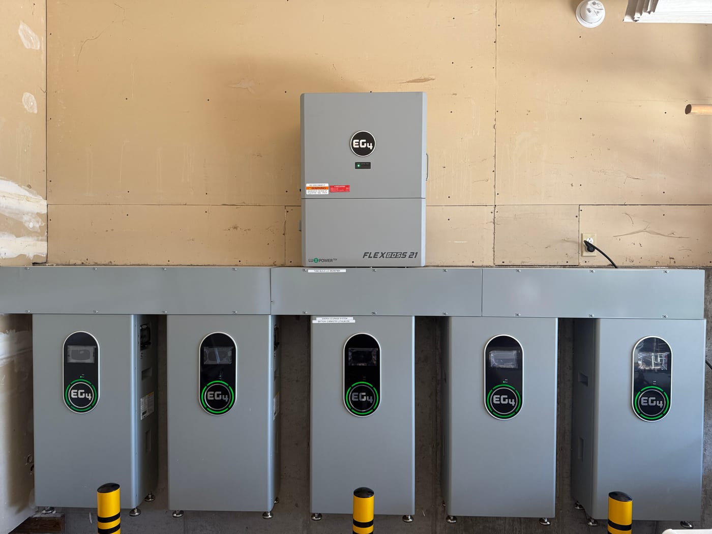 [EG4 FlexBOSS 21] Tight close-up of five EG4 batteries with FlexBOSS 21 inverter below, all green LEDs powered, brand logos clearly visible (image rotated)