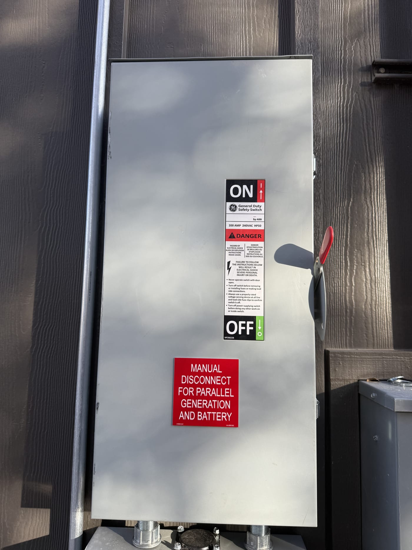 Close-up of manual disconnect switch with ON/OFF handle and red label reading Manual Disconnect for Parallel Generation and Battery
