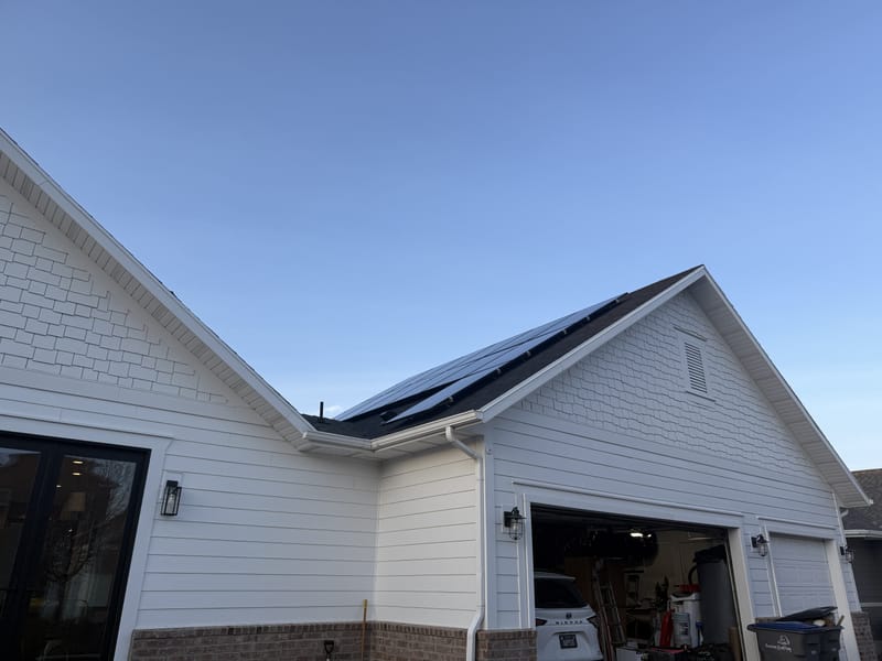 [Trina panels] Side view of house showing solar panels on roof section, rotated image, blue sky
